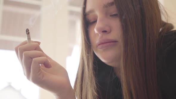 Portrait of a Drug Addicted Woman Smoking a Cigarette Indoors