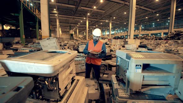 Junkyard Unit with Broken Office Machines and a Male Worker