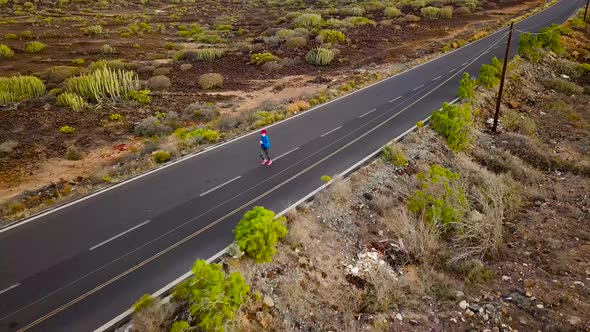 Aerial View of the Woman Runs Along the Deserted Asphalt Road at Sunset