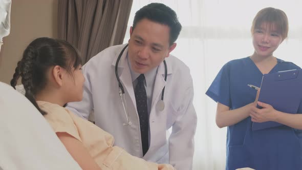 Asian doctor and nurse taking care of elderly male patient lying down on bed in recovery room.