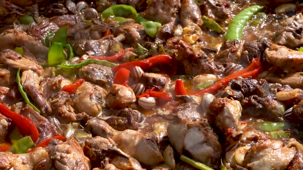 A close up slow motion panning shot of a delicious boiling hot Spanish Paella filled with peppers an