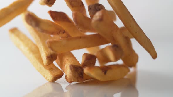 French fries falling on white surface. Slow Motion.