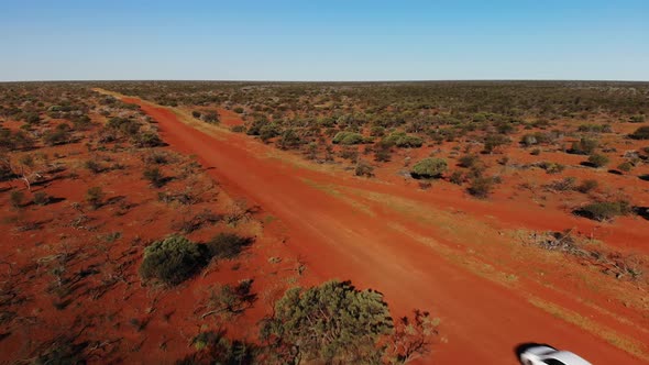 Lonely White Suv Car Driving an Unsealed Red Sand Road in the Wild Australian Desert