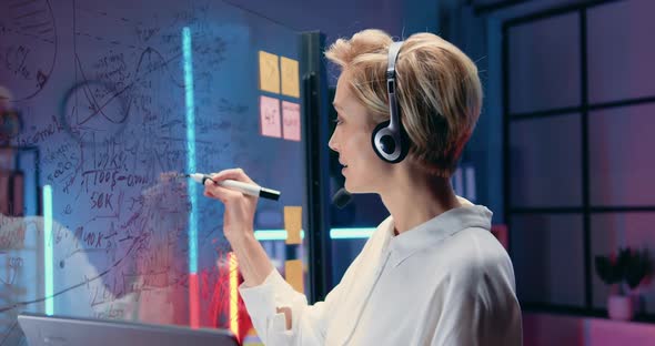 Female Office Manager in Headset Talking with Colleagues on Laptop, Discussing with them Strategy