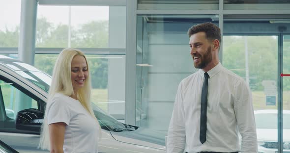 Salesman Helping Female Client to Choose Car at Showroom