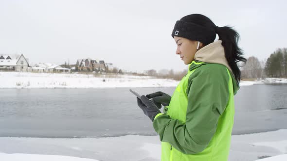 Side View of Sporty Woman Looking at Phone in Winter