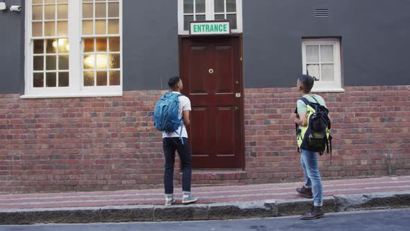 Two mixed race male friends walking and looking for hostel in the street