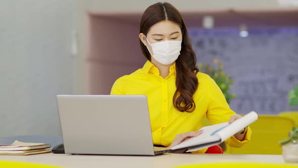 New normal of Asian woman in yellow shirt wearing surgical face mask meeting via VDO conference