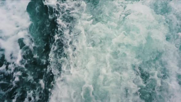 Slow motion froth splashing up behind boat creating blue and white imagery