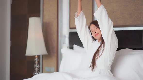 Asian woman relax on bed in bedroom interior