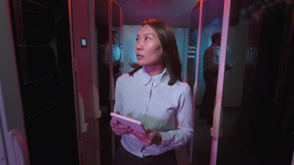 Asian Woman Checking Equipment in Data Center