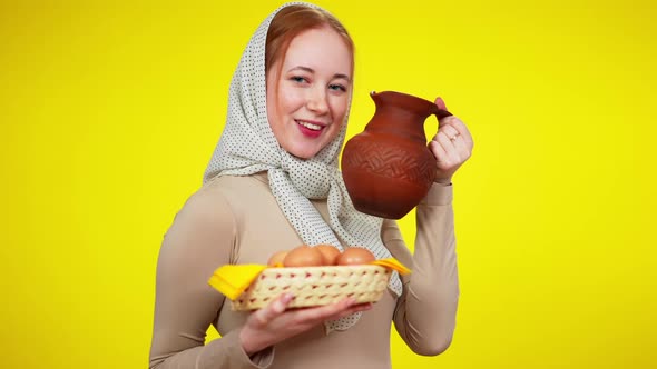 Charming Slim Cheerful Rural Woman Posing with Eggs and Milk Pot at Yellow Background