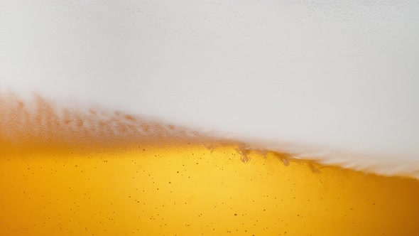 Extreme close-up beer in glass. Foam moving. Slow Motion. alt
