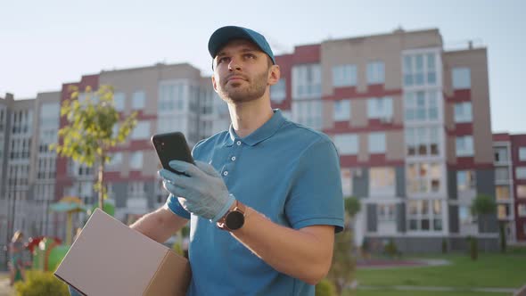 Male Courier Man is Looking for Mobile Phone to Deliver Address of Food From a Shop