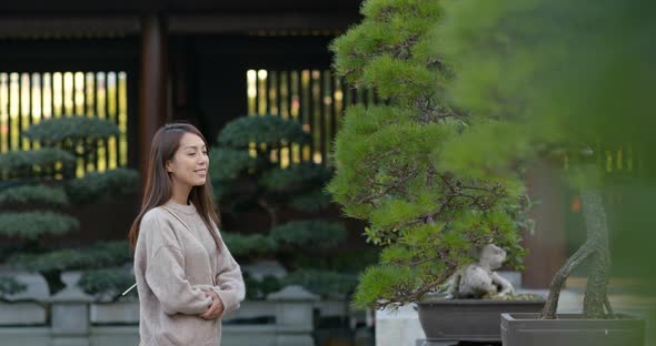 Woman look at the potted plant in chinese style garden 