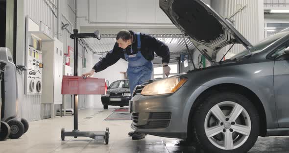 Car Service. Mechanic Is Adjusting Headlights. Low Beam, High Beam. Wide Shot