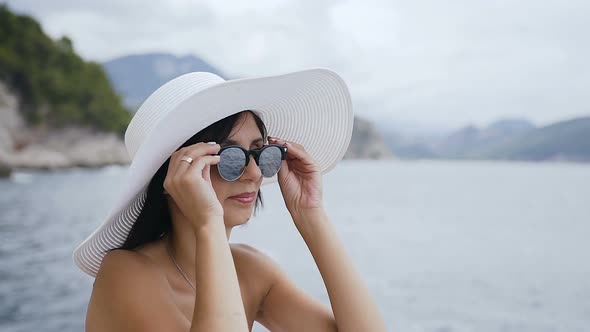 Cute Girl in Sunglasses and Hat on the Beach