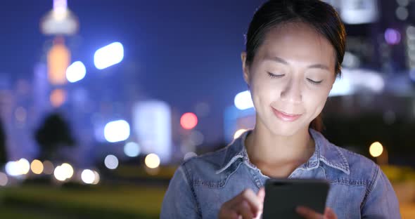 Woman use of mobile phone in Hong Kong city at night 