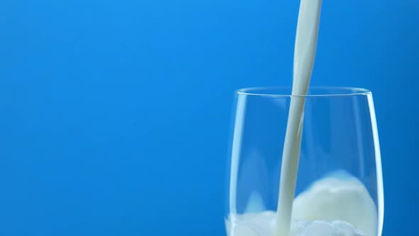 Pouring Milk in Glass on Blue Background