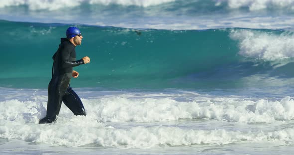 Male surfer running in the beach