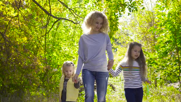 Happy Caucasian Family Walking Between the Trees in the Autumn Park