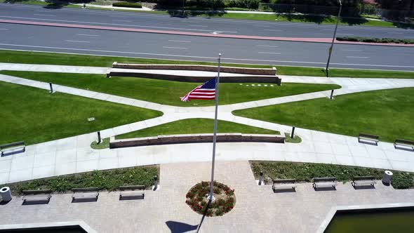 Aerial pull back of an American flag over a community lake