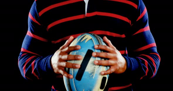 Angry professional rugby sportsman holds a rugby ball in his hands.