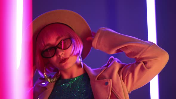 Eccentric Woman with Pink Hair Posing Near Ledcolorful Neon Lamps