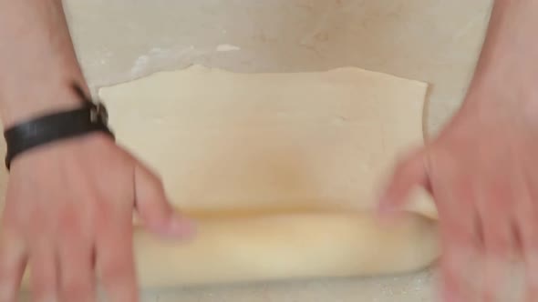 Kneading Dough with Rolling Pin on Wooden Table