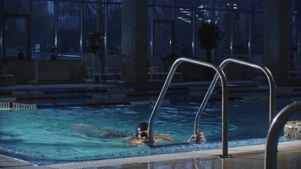 Swimming Sports Young Bearded Man Using a Ladder in the Pool As a Support to Jump Back Into the