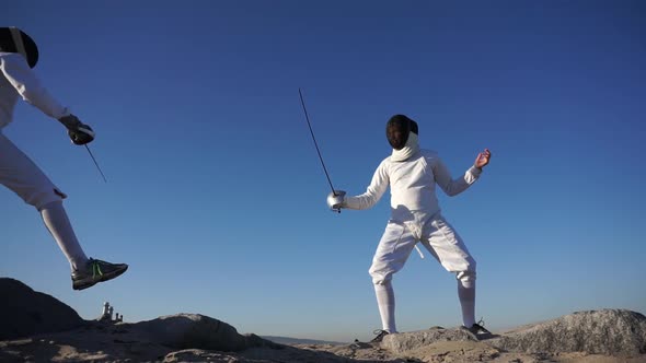 A man and woman fencing on the beach