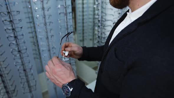 Man trying eyeglasses in store. Young man buying new glasses at optician store