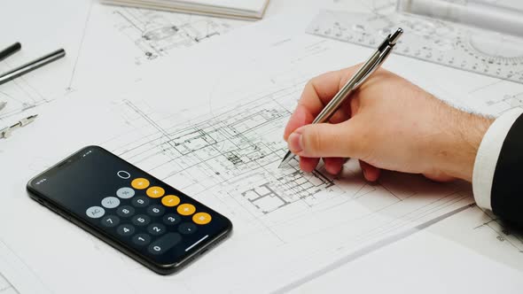 Architect Designer Counting on a Calculator Drawing Plan Blueprint Closeup