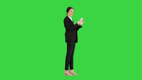 Smiling Businesswoman Checking Photos on Her Phone on a Green Screen, Chroma Key
