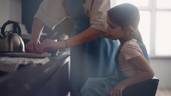 Careful Mother is Feeding Her Little Daughter Freshly Baked Pancake Woman and Child are Cooking