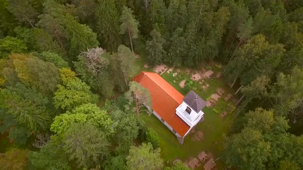 Aerial view of a traditional Chapel surrounded by a cemetery and a forest in Estonia.