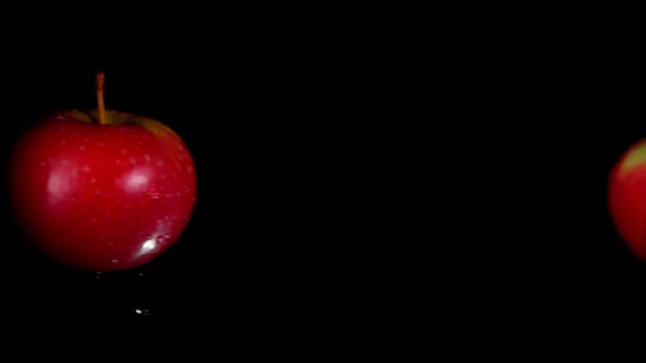 Two Delicious Red Apples Are Colliding on the Black Background in Slow Motion