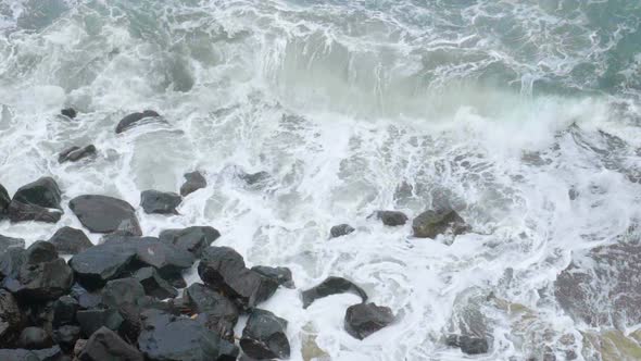Stormy Sea with Foamy Waves Breaking in Splashes Against Cliff, Slow Motion