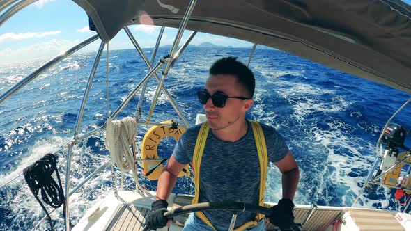 Front View of a Man in Sunglasses at the Wheel of a Sailing Vehicle