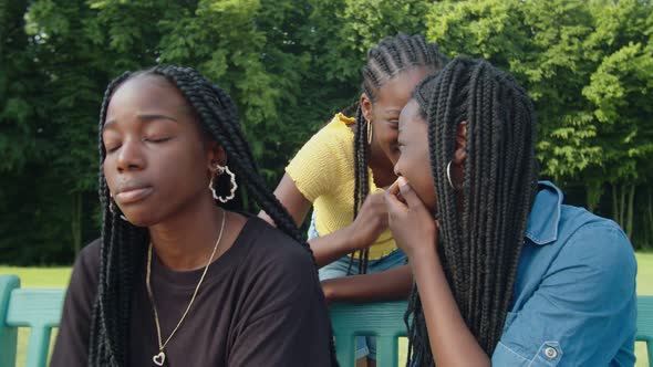 Mischievous Black Girlfriends Whispering Gossips About Friend Outdoors