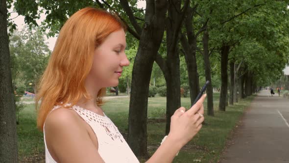 Redheaded Woman Texting on Mobile Phone