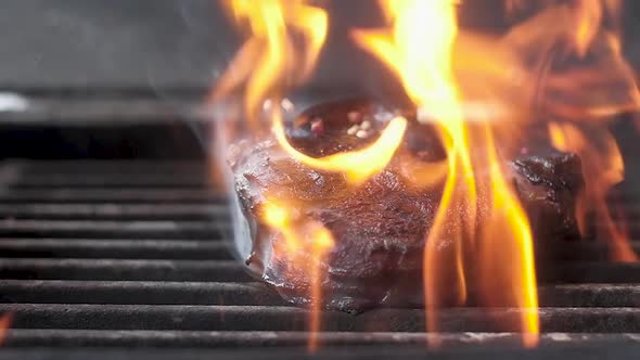 Chef sprinkles pepper on the meat with the bone on the grill