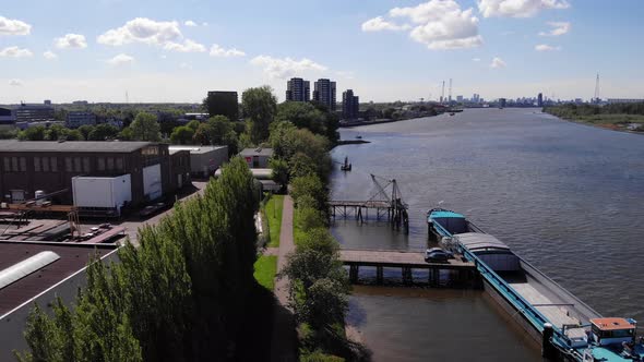 Cargo Ship Dock On The Riverport In Kinderdijk Village With Skyline On The Backdrop. descending dron