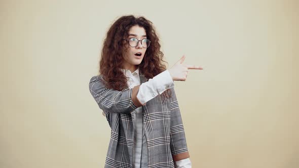 The Surprised Young Woman Shocked with Her Curly Hair in a Gray Jacket and White Shirt with Glasses