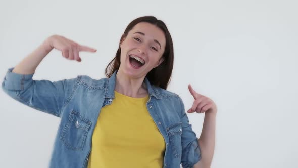 Happy Young Woman with Braces on Teeth on White Background Shows with Her Hands on Dental Metal