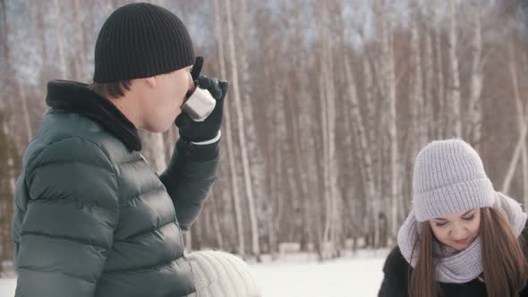 Young Family Drinking Hot Drinks From the Termos Outdoors Near the Forest