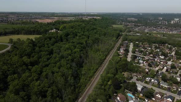 Aerial flyover Stoney Creek, beautiful green forest trees and Devil's Punch Bowl in background,Canad