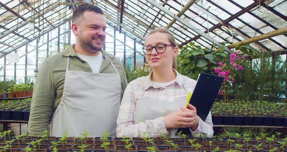 A Young Couple During an Online Live Broadcast  They Advertise Their Product in a Greenhouse