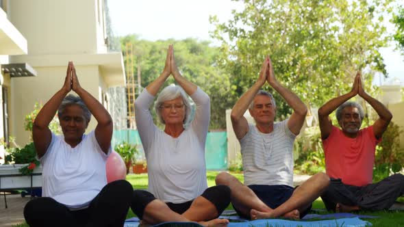 Senior friends performing yoga in garden 4k