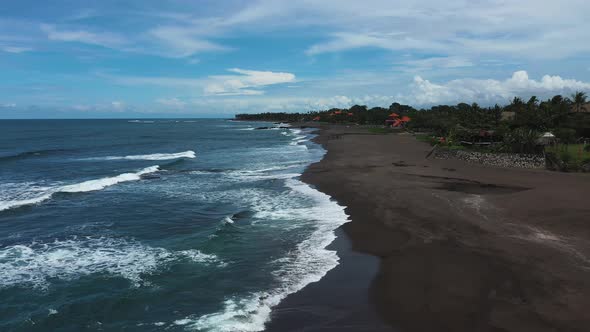 Pererenan Beach in Bali Indonesia showing dark volcanic sand, Aerial dolly out reveal shot